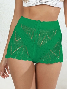 Dettaglio degli shorts all'uncinetto verde acceso con motivi geometrici traforati e laccio