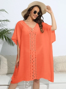Detail of crochet lace deep V-neck on vibrant orange loose beach cover-up dress