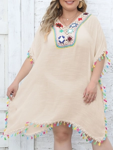 Detailed shot of beige bohemian beach cover-up featuring colorful crochet neckline and tassels