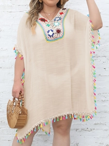 Detail of bohemian crochet V-neckline and colorful tassel fringe on a beach cover-up