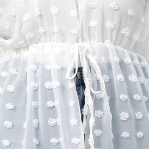 Detail of white Swiss dot chiffon cover-up featuring a drawstring waist and textured fabric