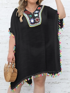 Detail of colorful hand-crochet V-neck and vibrant tassels on a black beach cover-up