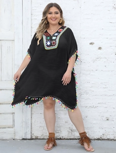 Close-up of colorful crochet embroidery on V-neck and fringe details of black beach cover-up