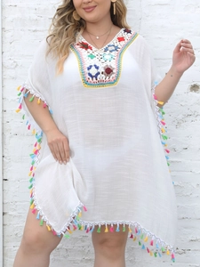 Detail of colorful crochet V-neckline and fringe trim on a white beach kaftan cover-up