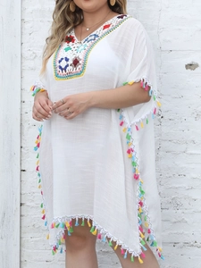Detail of colorful crochet neckline and vibrant tassel trim on a white beach cover-up