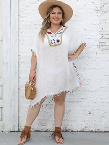 Macro view of colorful hand-crocheted neckline and fringe hem on white boho beach dress