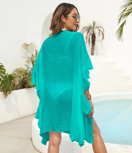 Teal ruffle sleeve beach cover up with pleated texture detail by a poolside setting
