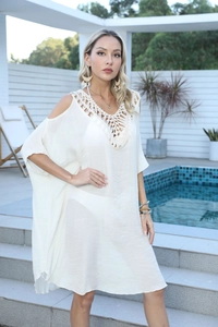 Détail de la dentelle au crochet bohème sur une robe de plage blanche à épaules dénudées