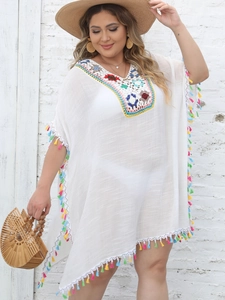 Detail of colorful crochet embroidery and vibrant tassels on a white beach cover-up dress