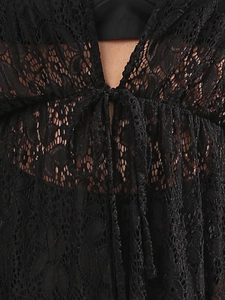 Detail of black lace beach cover-up featuring sheer floral patterns and front tie closure