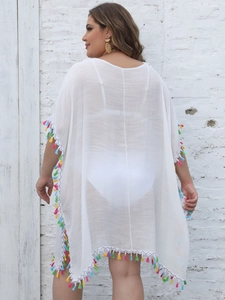 Detail of white beach cover-up featuring colorful tassel trim and textured fabric