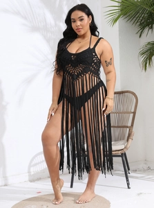 Detail of black crochet beach cover-up featuring geometric cutouts and long fringe hem