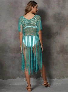 Detail of turquoise crochet beach cover-up featuring intricate hollow knit and long fringe