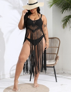 Detail of black crochet beach cover-up featuring geometric cutouts and long fringe hem