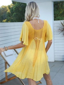 Detail of the bright yellow beach cover-up featuring intricate crochet cut-out back design