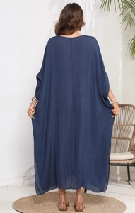 Back view of a long navy blue oversized beach cover-up dress in a relaxed scene