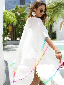 Detail of white beach cover-up with colorful pom-pom fringe and textured fabric