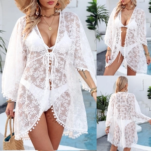 Detail of white floral lace beach cover-up with tassel ties and pom-pom trim accents