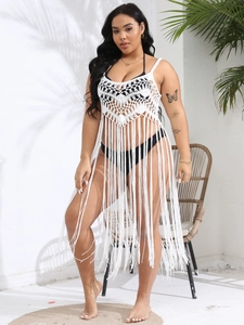 Detail of white crochet beach cover-up featuring fringe hem and hollow knit patterns