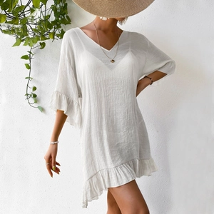 Détail de robe de plage blanche avec tissu texturé et manches cloche volantées