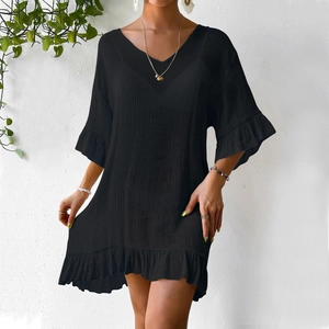 Détail d'une robe de plage noire à col en V avec tissu texturé et manches évasées à volants