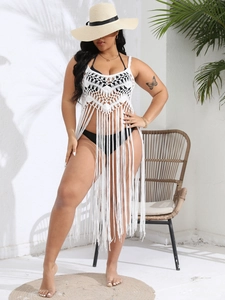 Detail of white crochet bikini cover-up featuring geometric lace patterns and long fringe