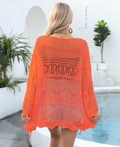 Close-up of bright orange crochet beach cover-up showing intricate geometric knit patterns