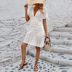 Close-up detail of white crochet lace beach dress featuring hollow wavy pattern and V-neckline