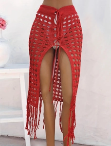 Detalle de falda roja de ganchillo calada con flecos largos y abertura lateral alta