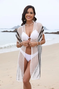 Detail of white crochet knit beach cover-up with black contrast trim and hollow pattern