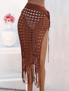 Detalle de falda playera de ganchillo marrón con calados y flecos largos decorativos