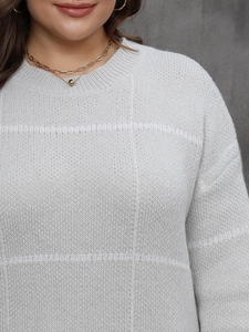 Detail of light grey knit dress featuring round neck and textured square pattern fabric