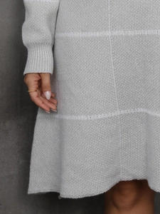 Detail of light grey knit dress featuring large plaid patterns and ribbed cuffs