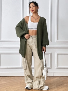 Détail d'un cardigan vert foncé en maille épaisse avec crop top blanc et pantalon cargo kaki