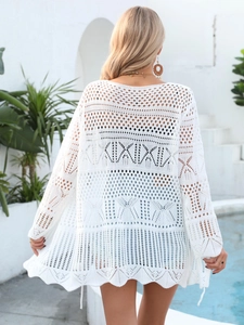 Close-up of intricate geometric crochet patterns on white beach cover-up cardigan