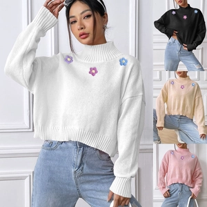 Detail of high collar knit sweater featuring 3D crochet flower patches in four colors