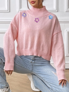 Close-up of pink high-neck sweater featuring colorful crochet flower embroidery details