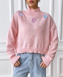 Close-up of pink turtleneck sweater with delicate purple floral embroidery details