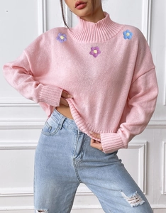 Detail shot of pink high-neck sweater with floral embroidery and ribbed edges