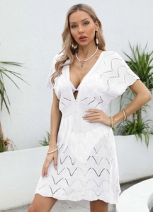 Close-up of white crochet beach dress featuring delicate wavy hollow patterns and deep V-neck