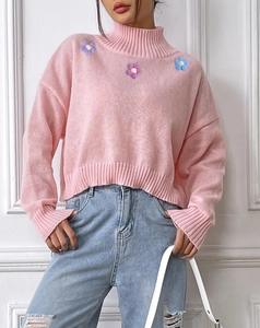 Detail of pink high neck knit sweater featuring colorful floral embroidery on the chest