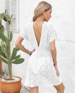 Detail of white crochet beach dress with deep V-neck and open back bohemian design