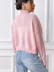 Detail view of pink high collar knit sweater with ribbed cuffs and drop shoulder design