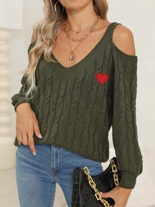 Detail of dark green cable knit sweater featuring cold-shoulder design and red heart patch