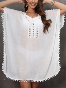 Detail of white crochet beach cover-up with pom-pom trim and delicate lace patterns