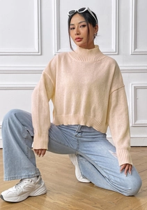 Detail of the high collar and soft knit texture on this cream-colored pullover sweater