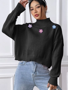 Detail of black turtleneck knit sweater featuring colorful 3D floral embroidery applique