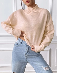 Detail of ribbed knit cuffs and neckline on a cozy cream high-neck sweater