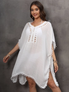 Detail of white crochet v-neckline and pom-pom trim on boho beach cover-up dress