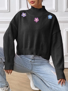 Women's black turtleneck knit sweater featuring colorful crochet flower patchwork detail